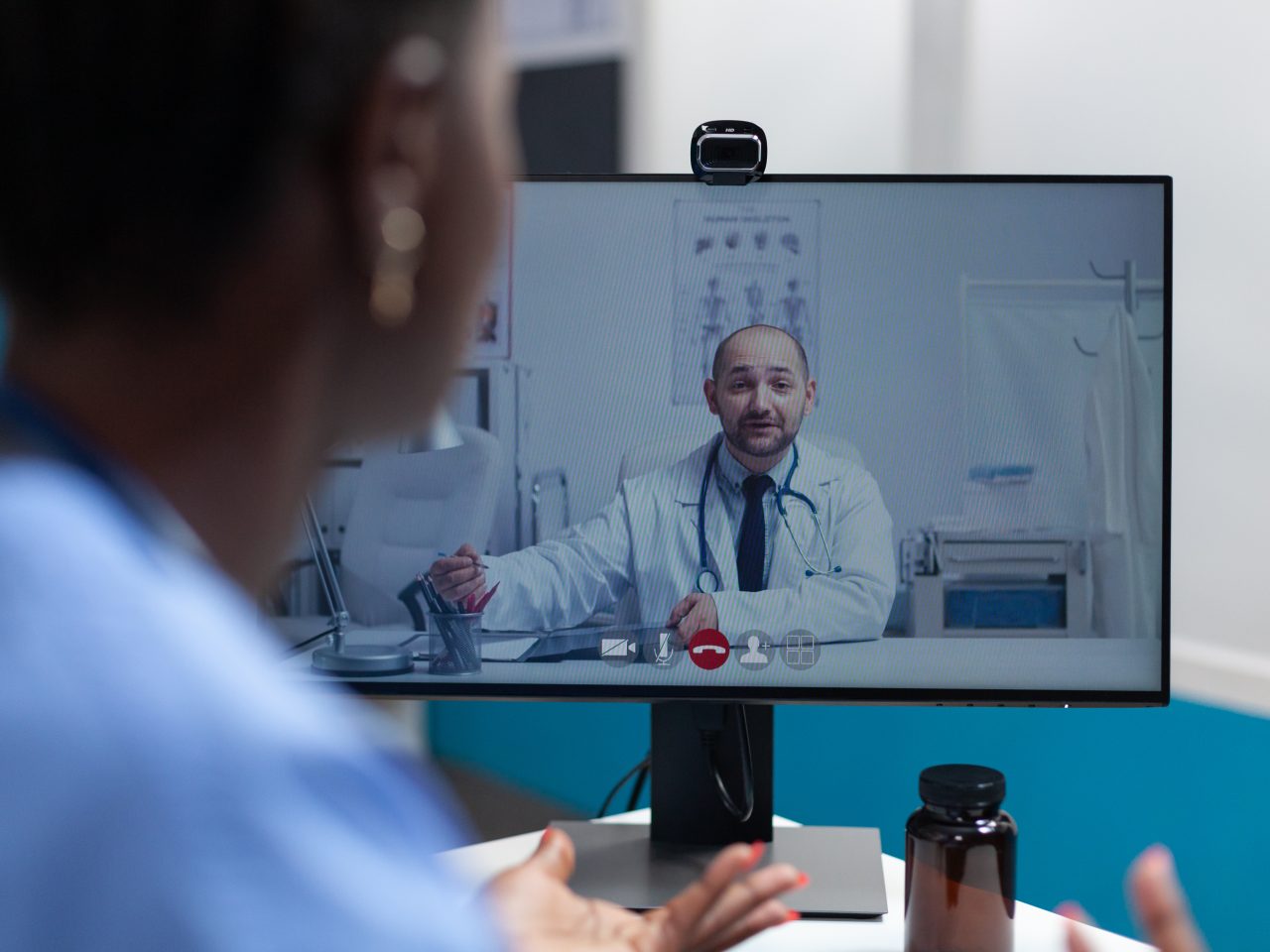 African american asisstant discussing flu symptoms with remote physician doctor during online videocall meeting conference working in hospital office. Telemedicine call on computer screen